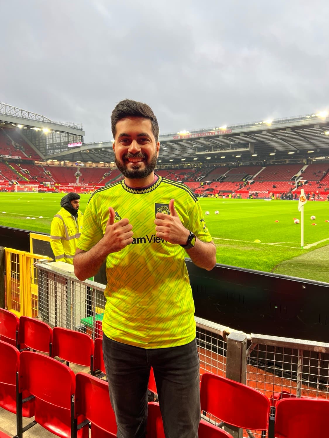The writer in a fluorescent Manchester United shirt, giving two thumbs up pitchside at Old Trafford before kick-off.